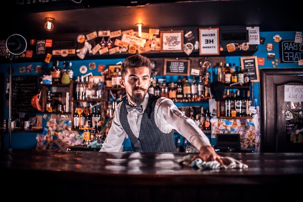 Experienced barman demonstrates the process of making a cocktail while standing near the bar counter in nightclub