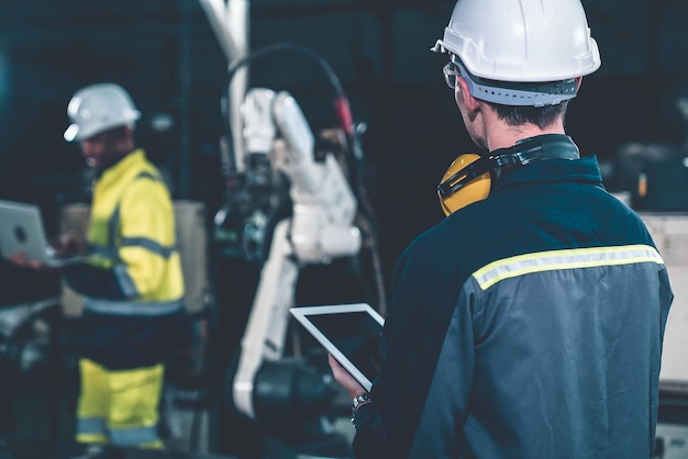 Fabriksarbejdere, der arbejder med en avanceret robotarm på et værksted