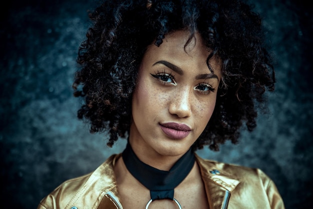 fashionable young woman with curly hair against wall