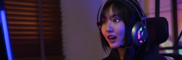Female cyber hacker gamer in headphone excited while playing games or hacking programming system