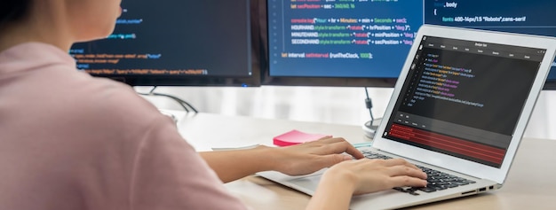 Female developer coding on laptop while computer display program Burgeoning