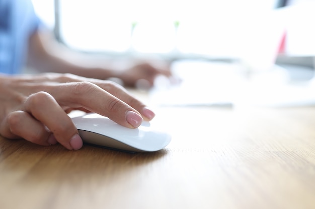 female hand holding computer mouse and typing on computer keyboard closeup work online concept