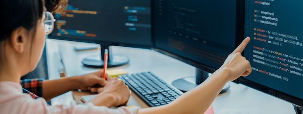 female programer taking a note while young skilled web developer present program while computer displayed program code at modern office company java script web design concept burgeoning