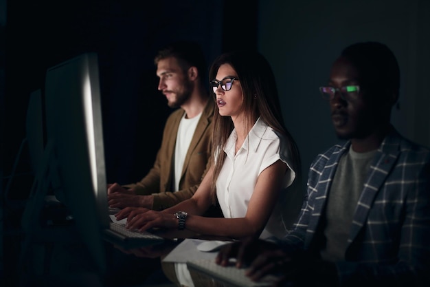 Financial team sitting in an office in front of a computer at nightpeople and technology