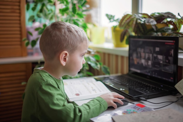 Fjernundervisning sødt skolebarn studerer lektier under online lektion derhjemme, social afstand