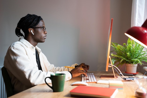 Focused african man freelance web developer writing code using computer sitting at home office