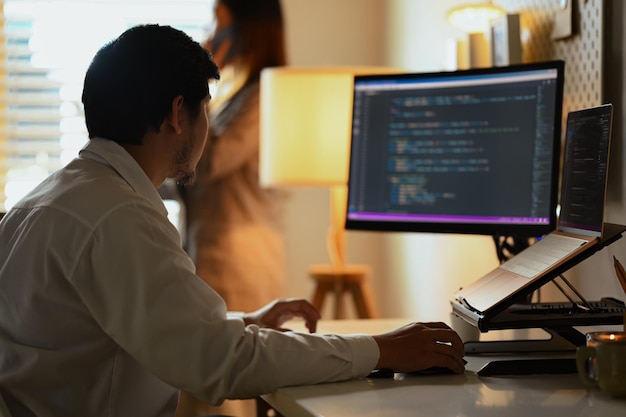 focused software developers man programming on desktop computer in dark office