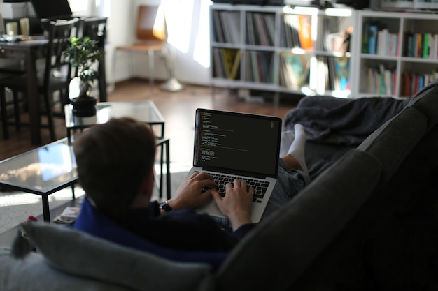 Freelancer, der arbejder hjemmefra og skriver kode på sofaen