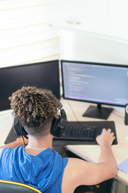 from above software engineer sitting at desk and typing on computer keyboard while creating code during work at home