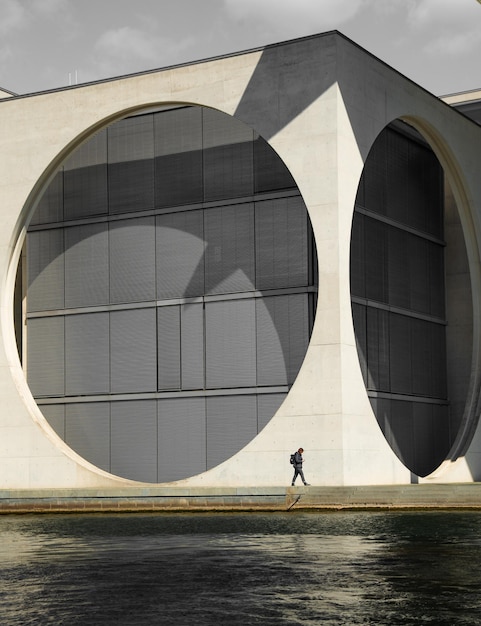Full length of man walking by modern building in city against sky