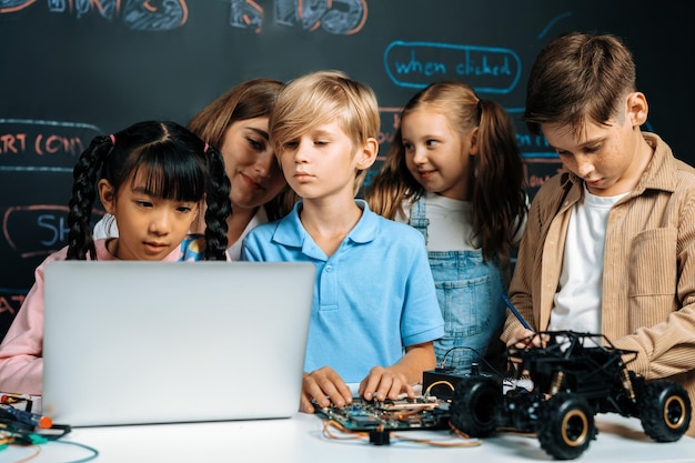 Girl wear pink cloth use laptop for coding while teacher watch her erudition