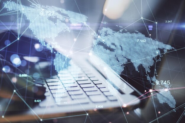 Global business and technology concept Side view and close up of hands at desktop using laptop with glowing digital map Double exposure