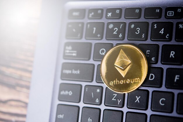 Golden Ethereum ETH cryptocurrency coin on a dark keyboard of laptop