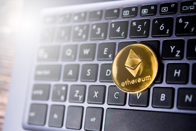 Golden Ethereum ETH cryptocurrency coin on a dark keyboard of laptop