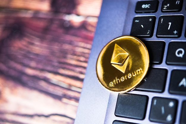 Golden Ethereum ETH cryptocurrency coin on a dark keyboard of laptop