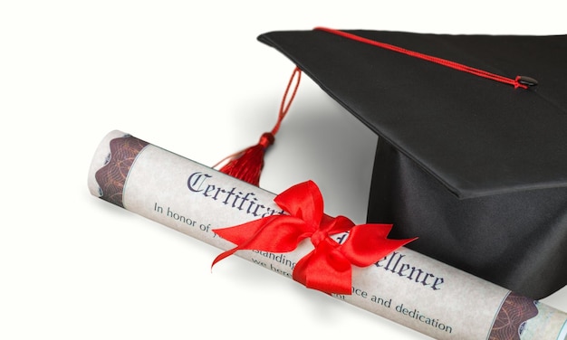 Graduation hat and diploma on background