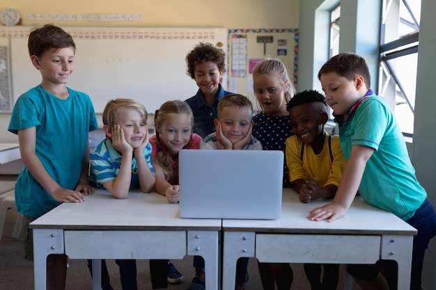 Group of schoolchildren using a laptop computer in an elementary school classroom
