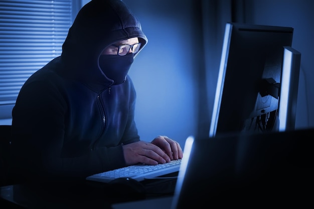 Hacker in front of his computer. Dark face