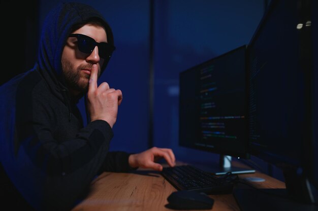 hacker sitting at desk in dark atmosphere A computer programmer or hacker Anonymous computer hacker