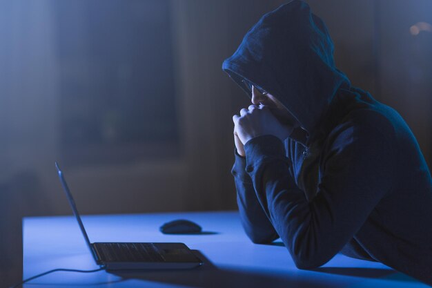 hacker with laptop computer in dark room