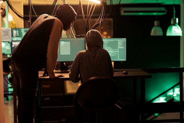 Hackers coding malicious software cracking database password online server illegal access data breach Cybercrime internet thieves hacking computer network system at night time