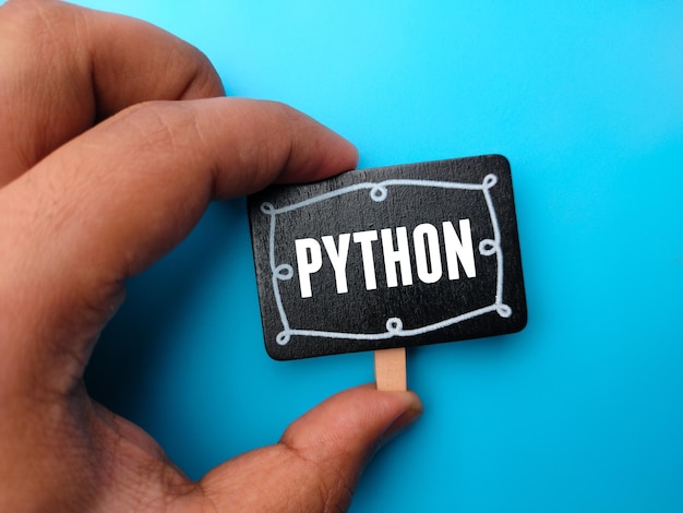 Hand som håller träskiva med ordet PYTHON på en blå bakgrund