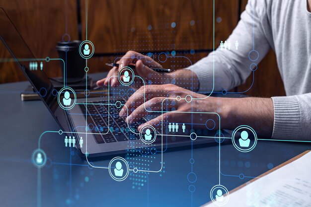 Händerna på en HR-specialist knappar på tangentbordet på internet för att hitta de bästa kandidaterna för att skapa ett internationellt nätverk i rekryteringsprocessen. Konceptet med framgång. Hologramikoner för sociala medier