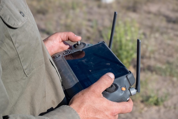 Hands of operator piloting agricultural drone