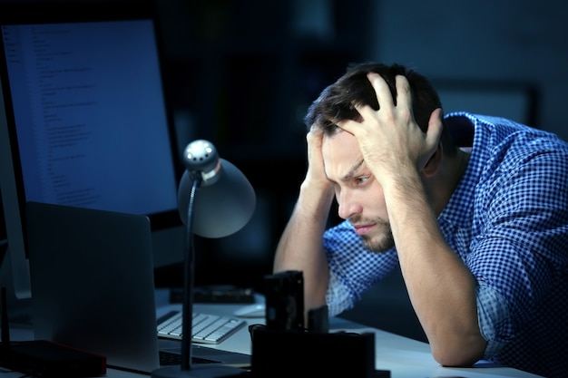Handsome young programmer working at home late in evening