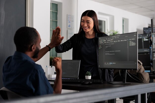 Happy system engineers celebrating successful code script compiling, doing highfive hand gesture after system development. Team of web developers analyzing algorithm and creating app server interface.