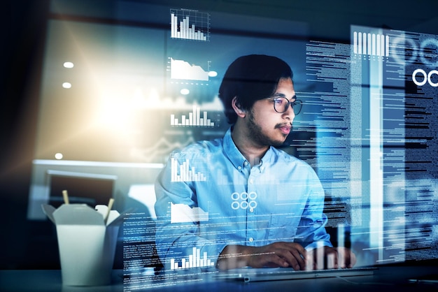 Hes going to pull an all nighter Shot of a focused young programmer working on his computer in the office during the night