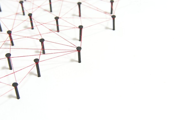 High angle view of nails connected with thread on white background