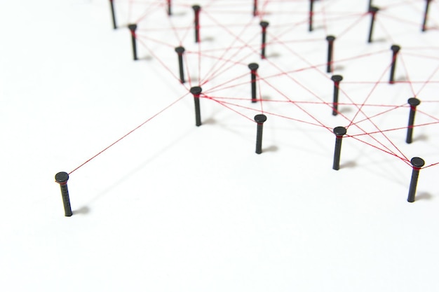 High angle view of nails connected with thread on white background