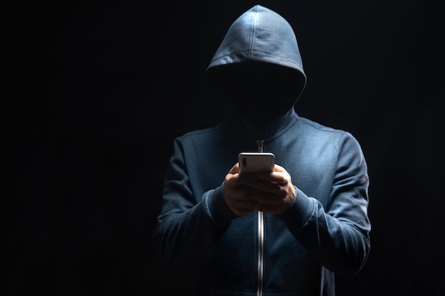 Holds the phone on a dark scene. hacker concept