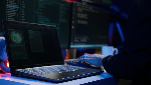 Hooded hacker taking laptop out of suitcase prepared to launch DDoS attack