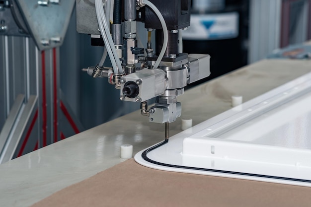 Industrial robotic dosing dispenser machine applies a hardening sealant to the metal door blank