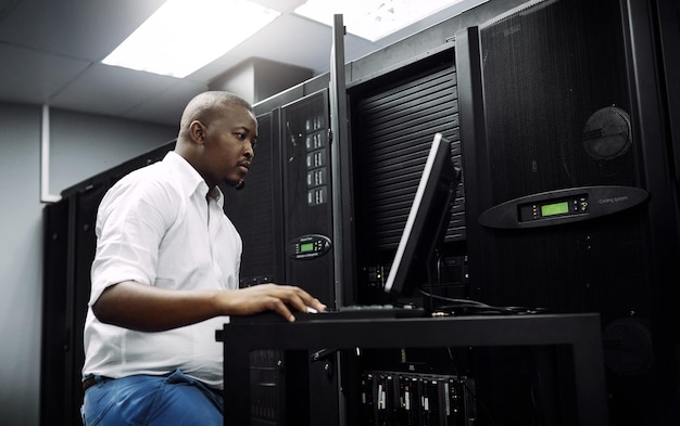 Ingeniør sort mand eller kodning på bærbar computer i serverrum for big data netværksfejl eller digitalt websted Kode IT support eller tekniker, der skriver på computer og tester programmering eller softwareudvikling