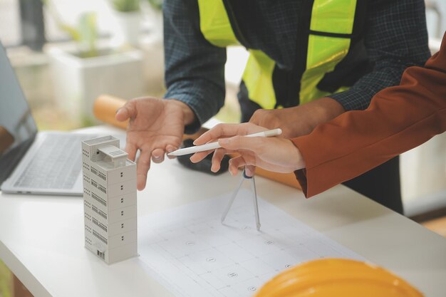 Ingenjörer – teamarbete – möte. En ritning, ett möte för ett projekt med en partner, modellbygge och tekniska verktyg på en arbetsplats. Koncept för konstruktion och struktur