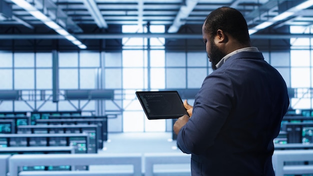 IT expert in server hub facility looking for network bugs with tablet