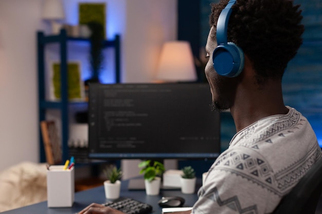 It-kodeudvikler med headset programmerer koder til firewall-server på computer, der arbejder hjemmefra. Hacker-mand, der skriver infografik javascript og kunstig intelligens algoritme