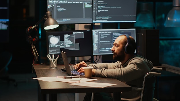 it web developer writing source code in office, dealing with physical disability at night. software engineer wheelchair user working late to develop new server database with html script.