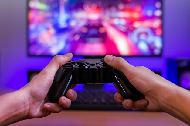 joypad in hands gaming concept computer display with racing game and rgb light in background