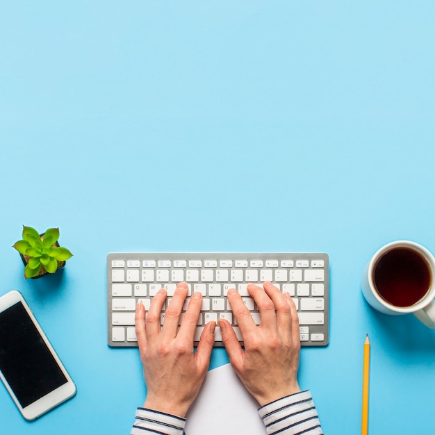 Kvinde arbejder på kontoret på en blå baggrund. Koncept arbejdsplads, arbejde ved en computer, freelance