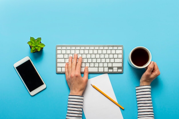 Kvinde arbejder på kontoret på en blå. Koncept arbejdsplads, arbejde ved en computer, freelance