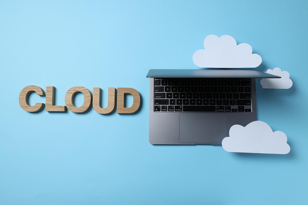 Laptop with paper clouds on a blue background place for text