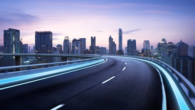 Light trails on elevated road by illuminated buildings against sky in city