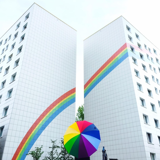 Low angle view of rainbow colors against tall buildings