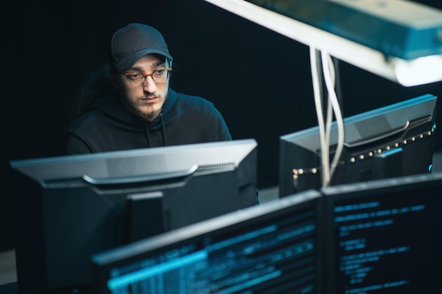 male hacker using keyboard to type a dangerous malware into bank system