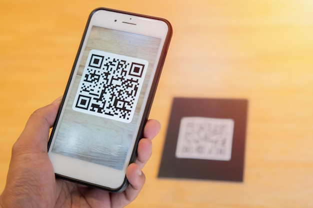 Male hand holding a mobile phone with qr code on the screen scanning the qr code