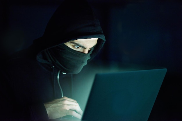 Man laptop and hoodie on black background for hacking phishing and malware with virus Hacker technology and software for cyber crime hacktivism or information spy with programming or coding